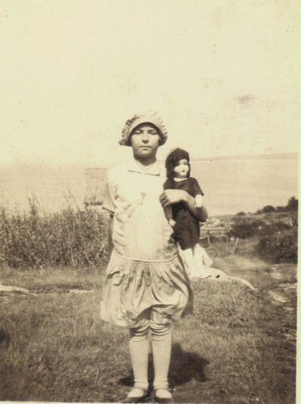 Before: Girl holding a doll beside the sea