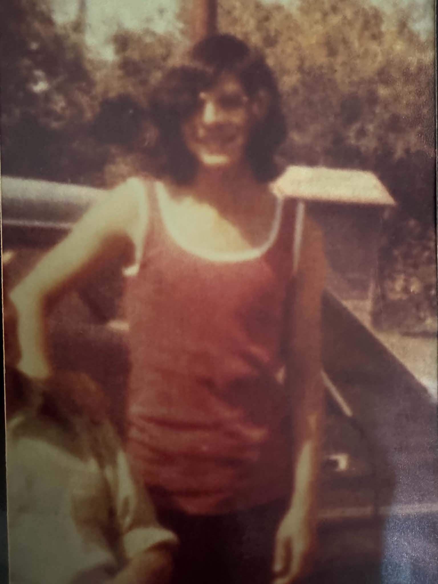 Before: faded portrait of a person in a red top beside a car